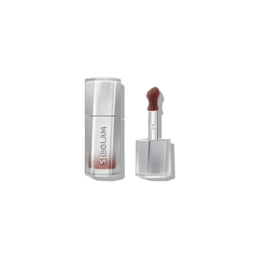 SHEGLAM Glass Lock Air Gloss – Sepia Kiss, soft brown-rose nude high-shine lip gloss in a sleek tube with a glassy, mirror-like finish on a clean background.
